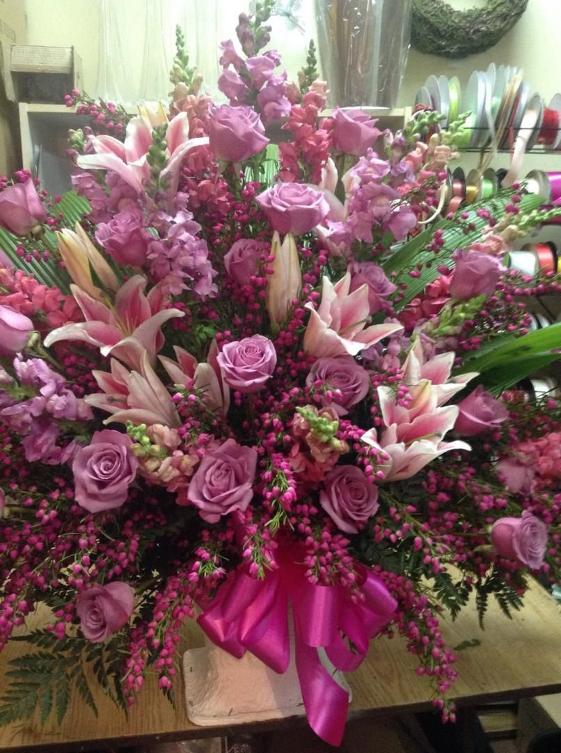 Un grand bouquet de fleurs violettes avec un nœud rose sur une table.