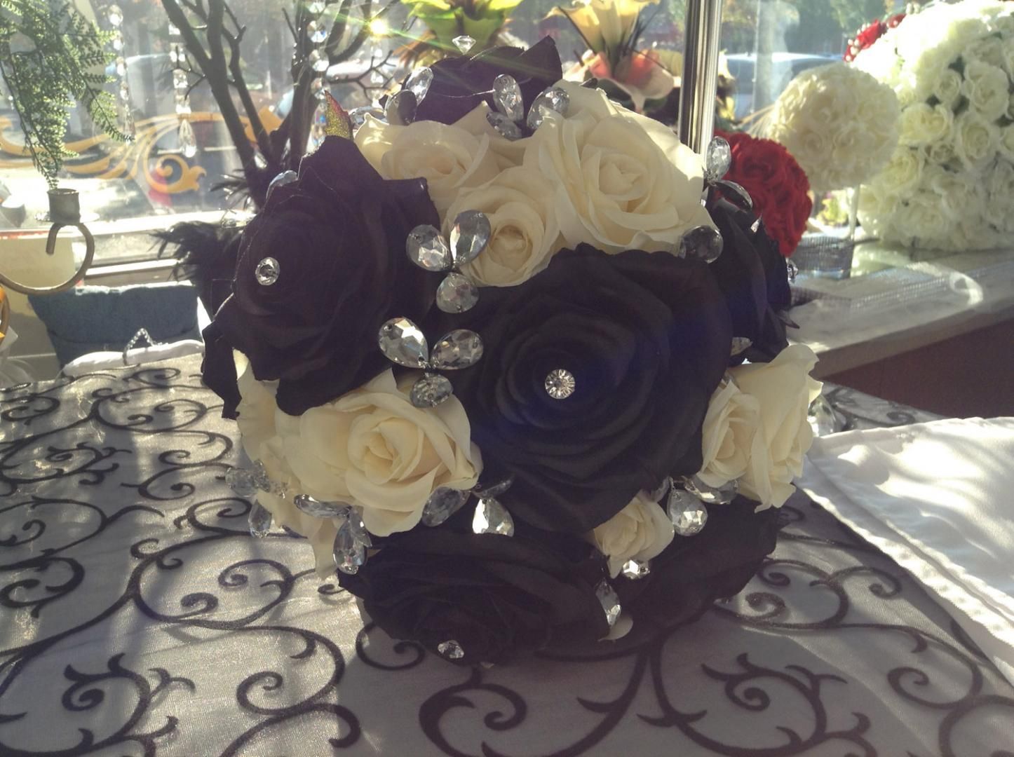 Un bouquet de roses noires et blanches avec des strass est posé sur une table