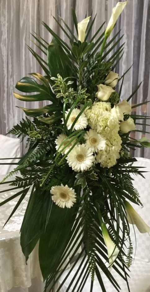 Un bouquet de fleurs blanches et de feuilles vertes est posé sur une table.