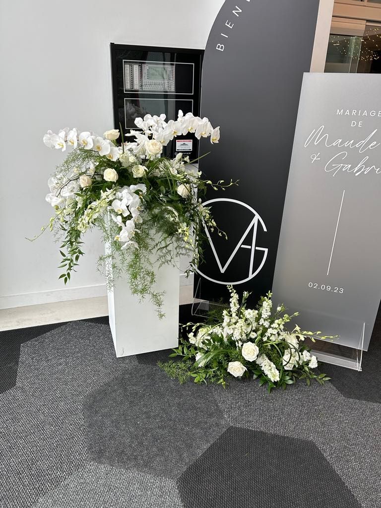 Un bouquet de fleurs blanches est posé sur une table devant un panneau.