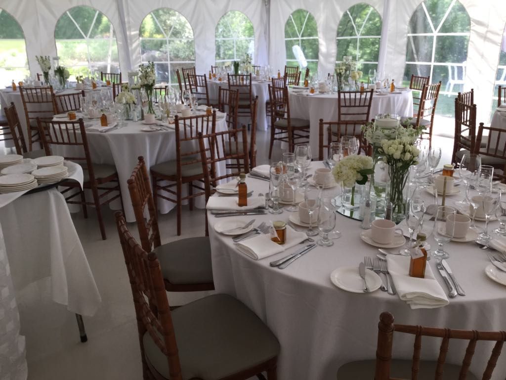 Une grande tente avec des tables et des chaises installées pour une réception de mariage.