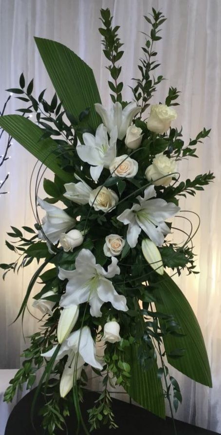 Un bouquet de fleurs blanches et de verdure est posé sur une table.