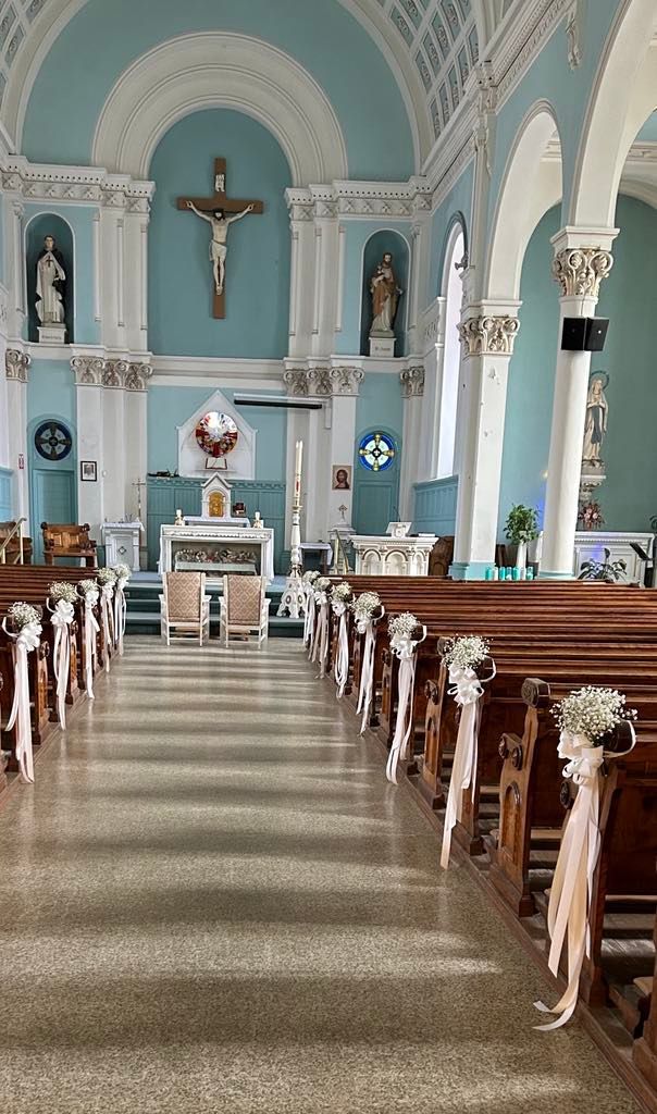 L'intérieur d'une église décorée pour un mariage avec des fleurs sur les bancs.