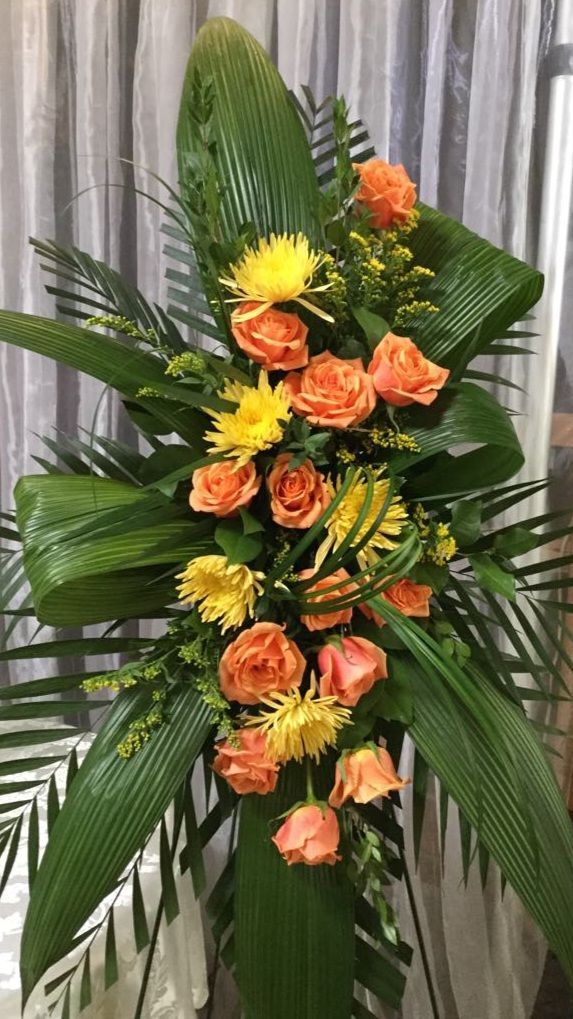 Un vase rempli de roses oranges et de marguerites jaunes est posé sur une table.