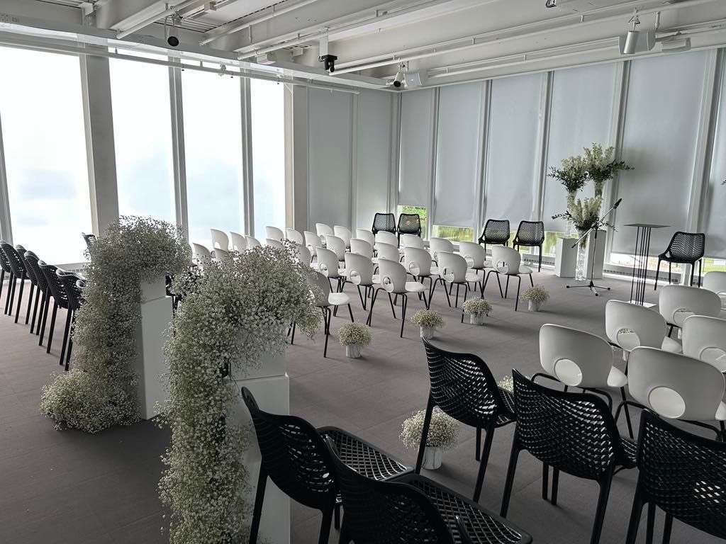 Une salle remplie de chaises et de fleurs pour une cérémonie de mariage.