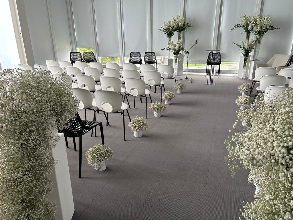 Une pièce avec des rangées de chaises et des fleurs sur le sol