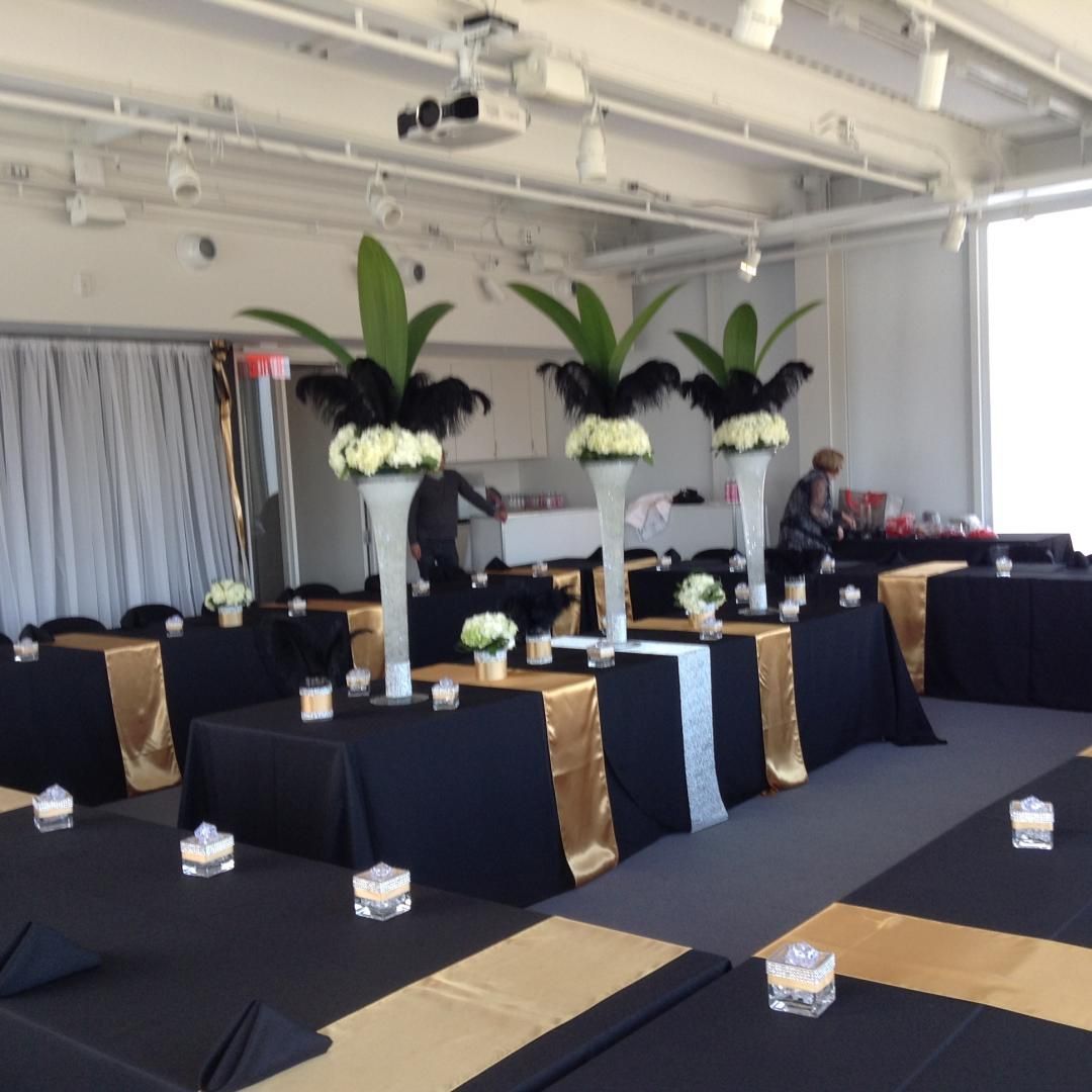 Une pièce avec des tables noires et dorées et des fleurs dans des vases