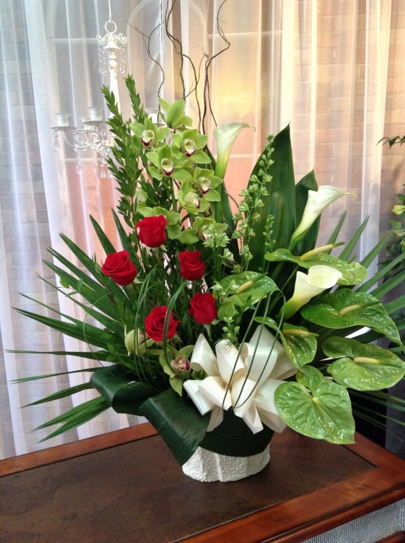 Un vase rempli de fleurs et de feuilles est posé sur une table.