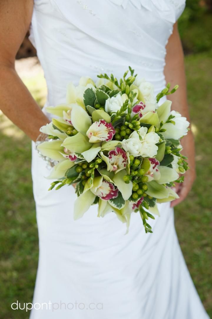 Une femme en robe blanche tient un bouquet de fleurs