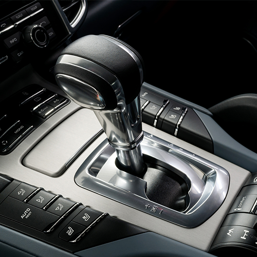 Shiny car gear shift in a modern vehicle interior. Silver and black accents on the gear shift and surrounding console.