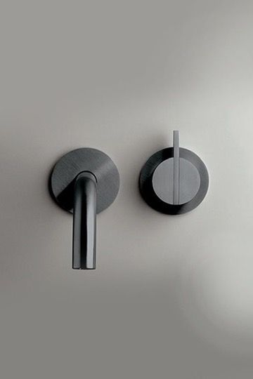 Donkere metalen Gun metal kraan en knop gemonteerd op een lichtgrijze muur.