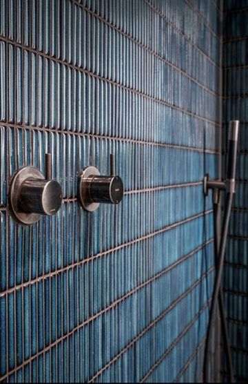 Douchewand met blauwe witkat tegels, zilverkleurige rvs kraanbediening en douchekop van Hotbath