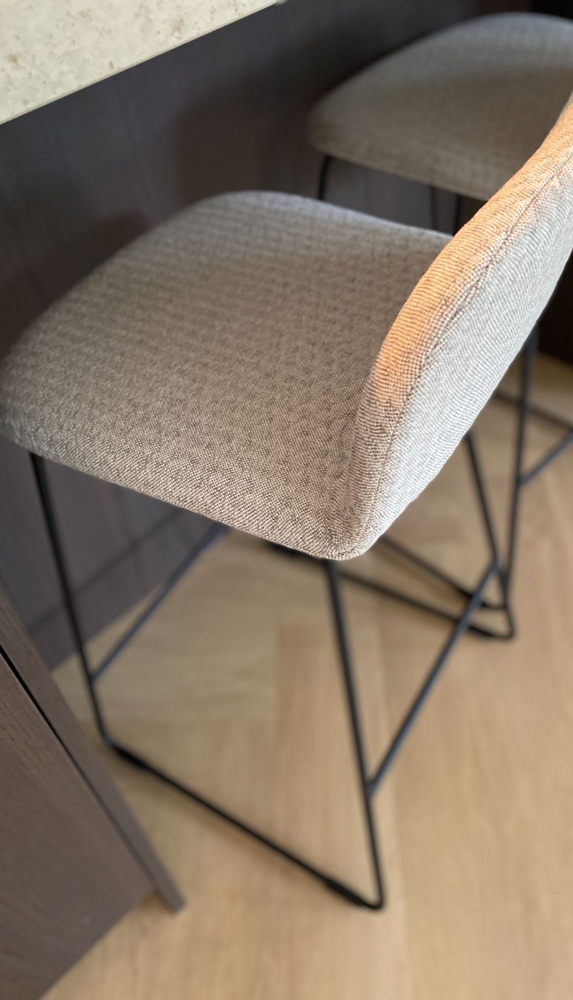 Twee grijze barkrukken met een zwart metalen frame in een moderne keuken.