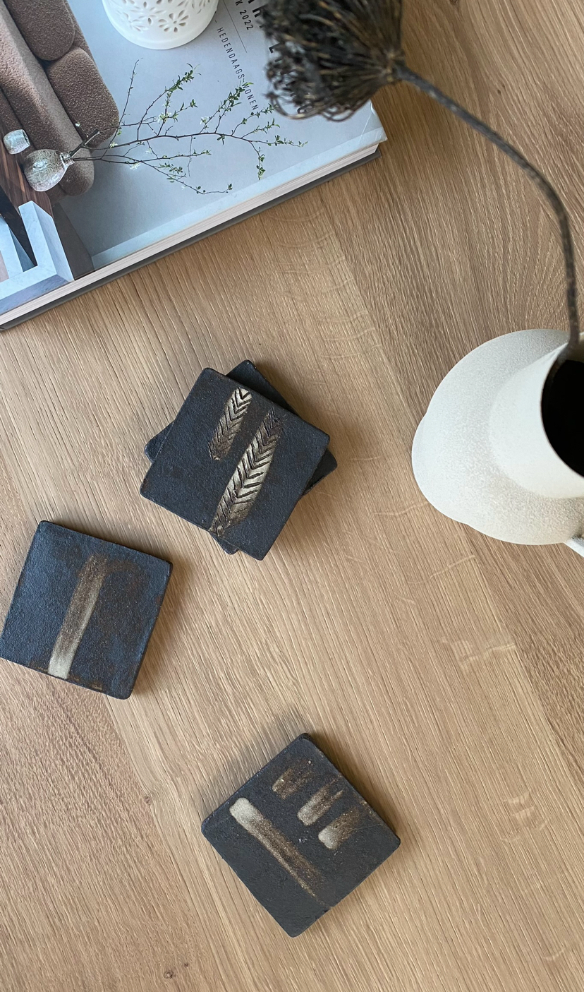 Een set onderzetters op een houten tafel naast een vaas.