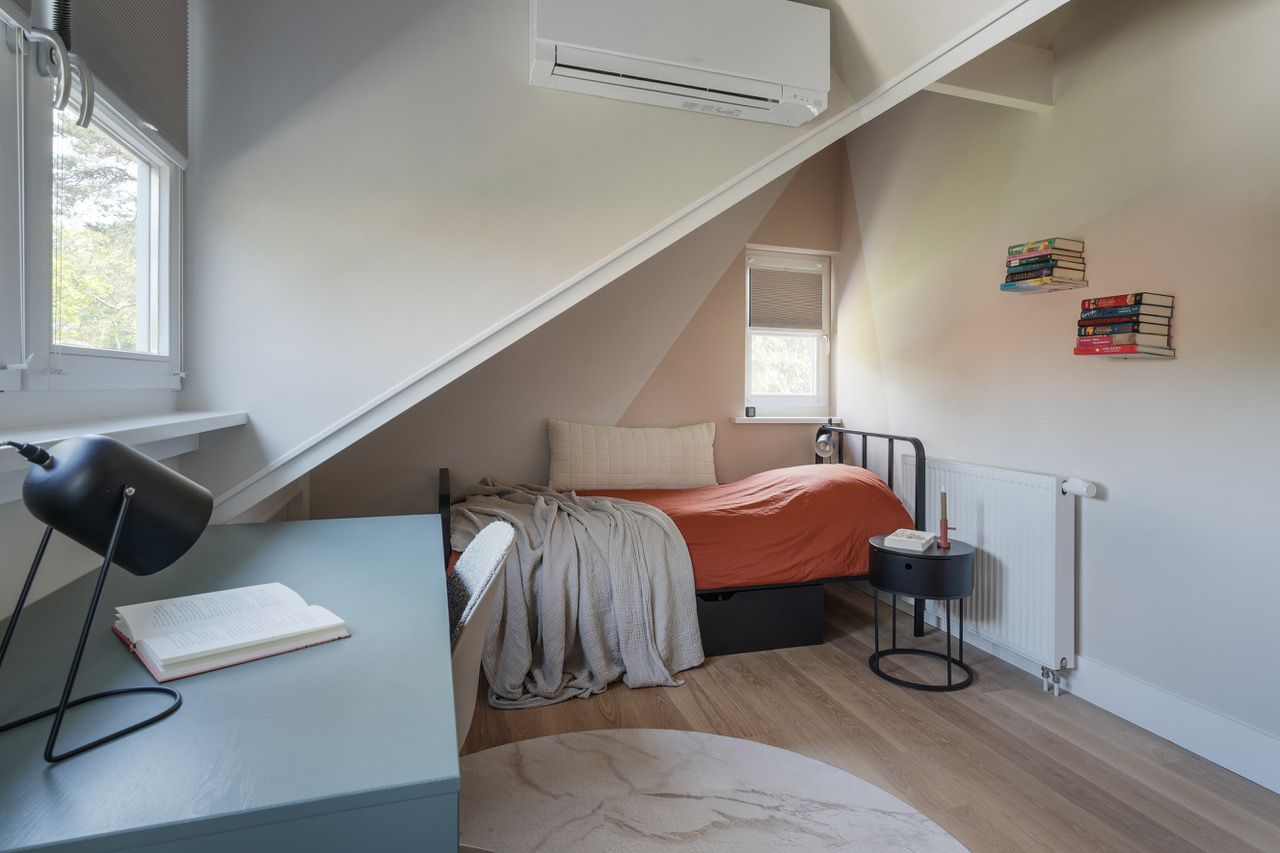 Een gezellige, meisjes tiener slaapkamer met een bed, bureau en rond vloerkleed in neutrale tinten.