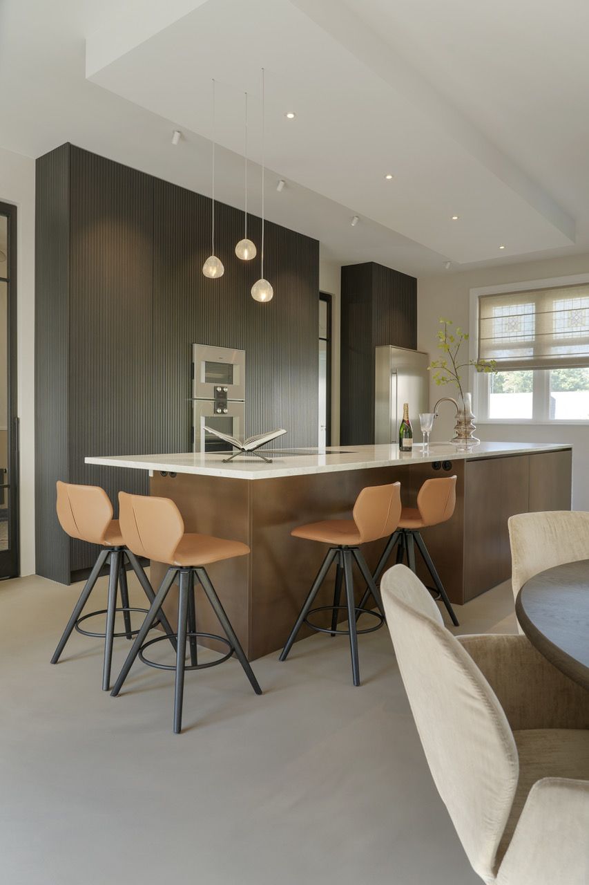 Moderne keuken met een donkerhouten kookeiland, barkrukken en hanglampen.
