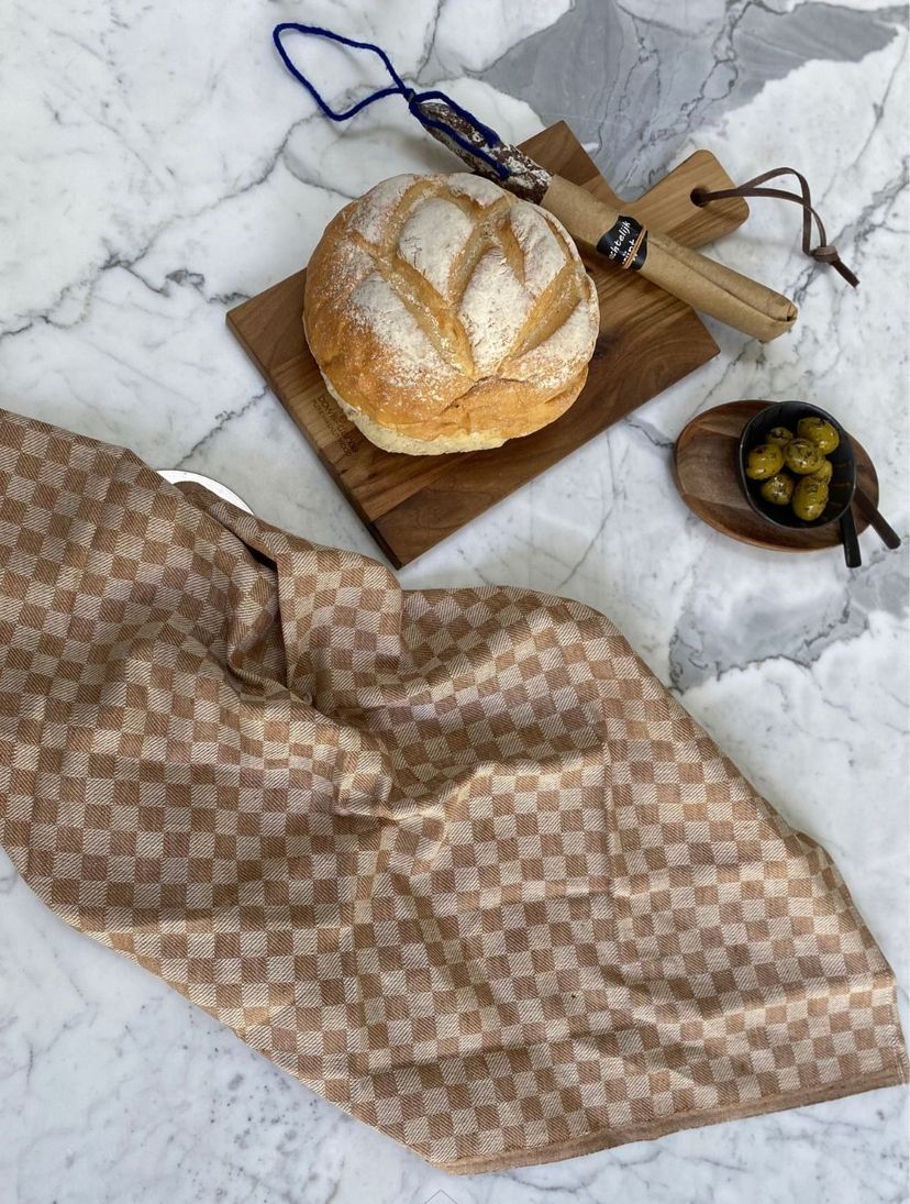 Brood op een snijplank met olijven en een theedoek op een marmeren keukeneiland