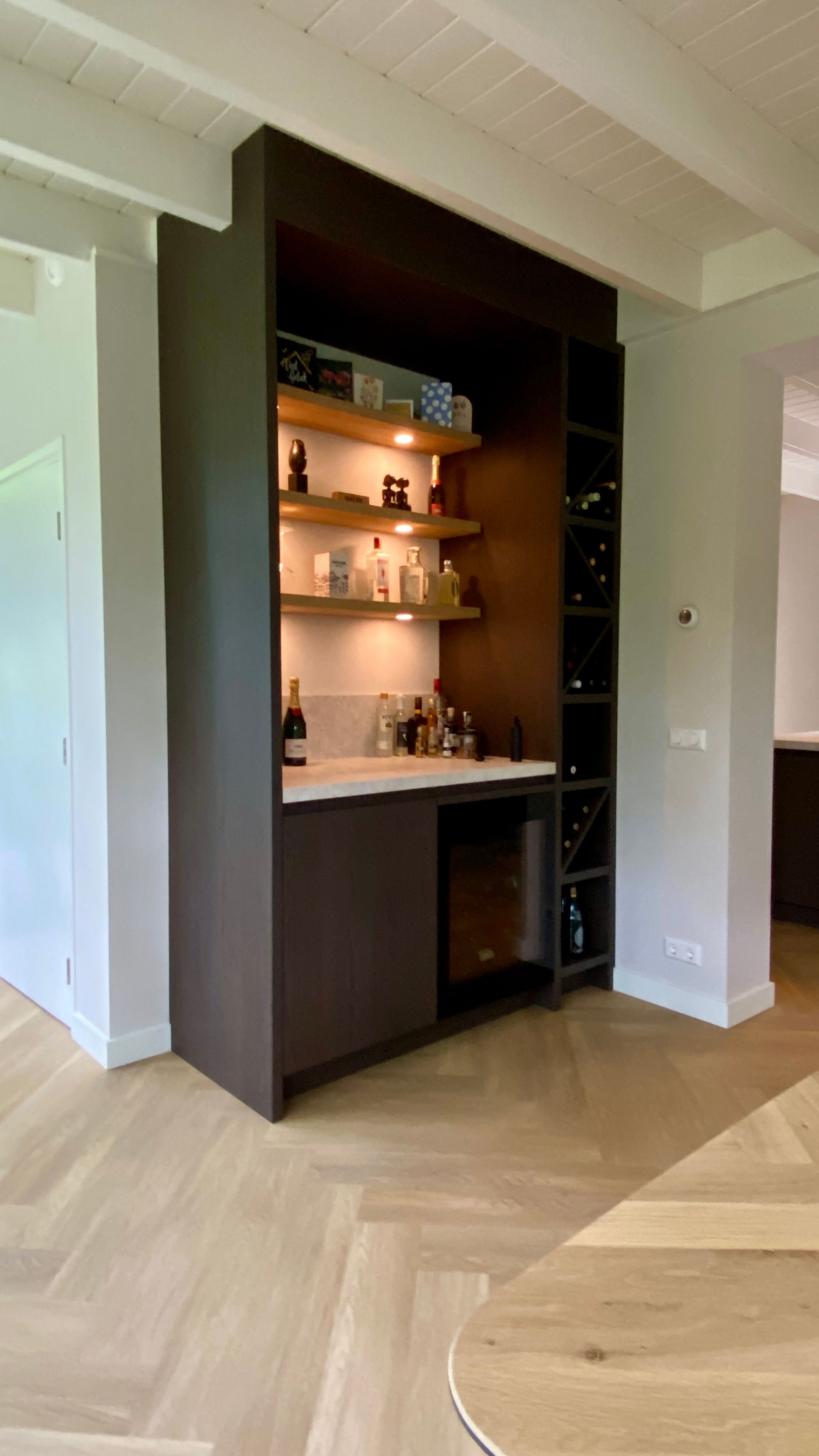 Donker houten bar met sterke drank, wijnrek en kleine wijnkoelkast