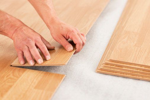 Man's Hands Laying Yellow Laminate Flooring — Fort Wayne, IN — G & W Flooring
