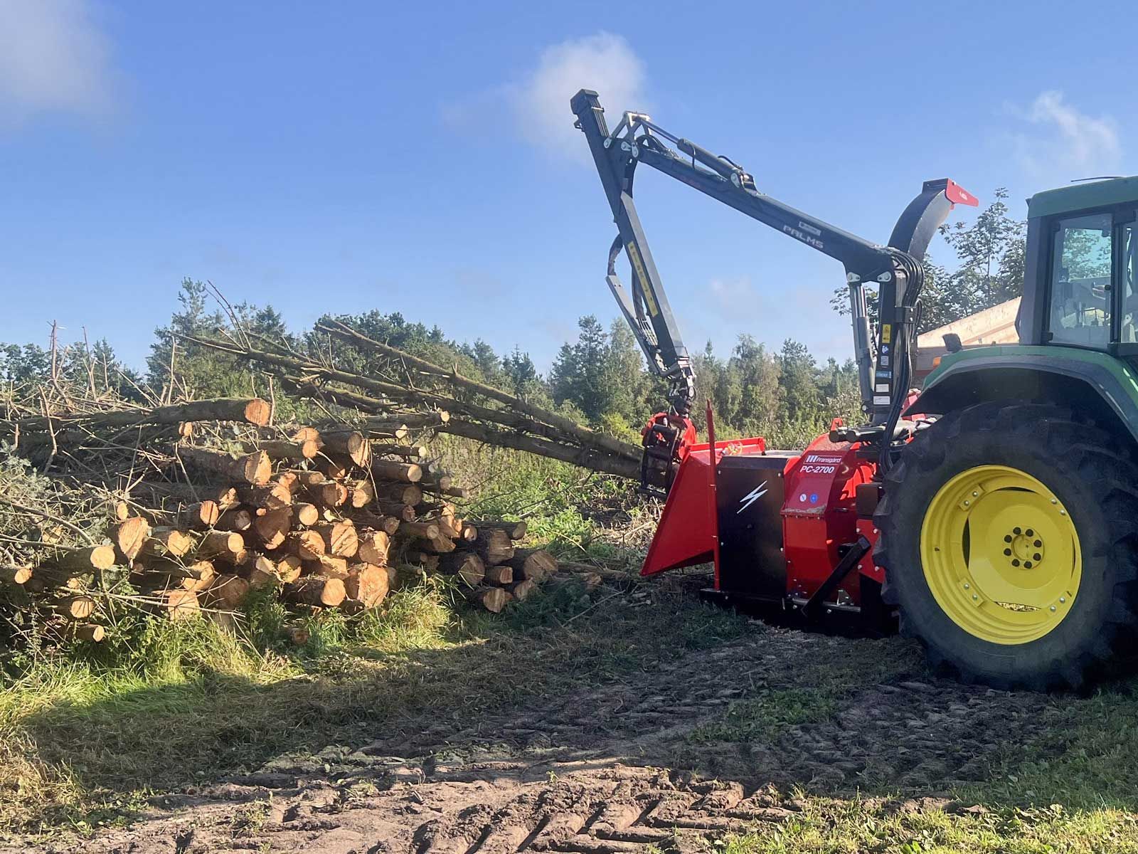 A wood chipper is feeded with a pile of logs .