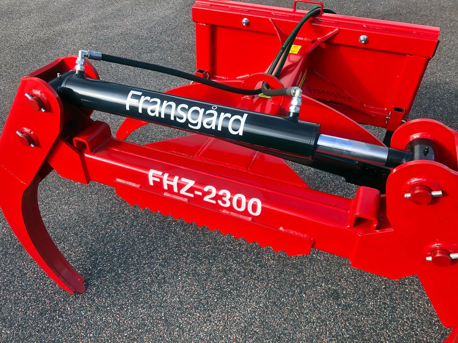 En rød Fransgård FKZ-2300 maskine med en hydraulisk cylinder påsat