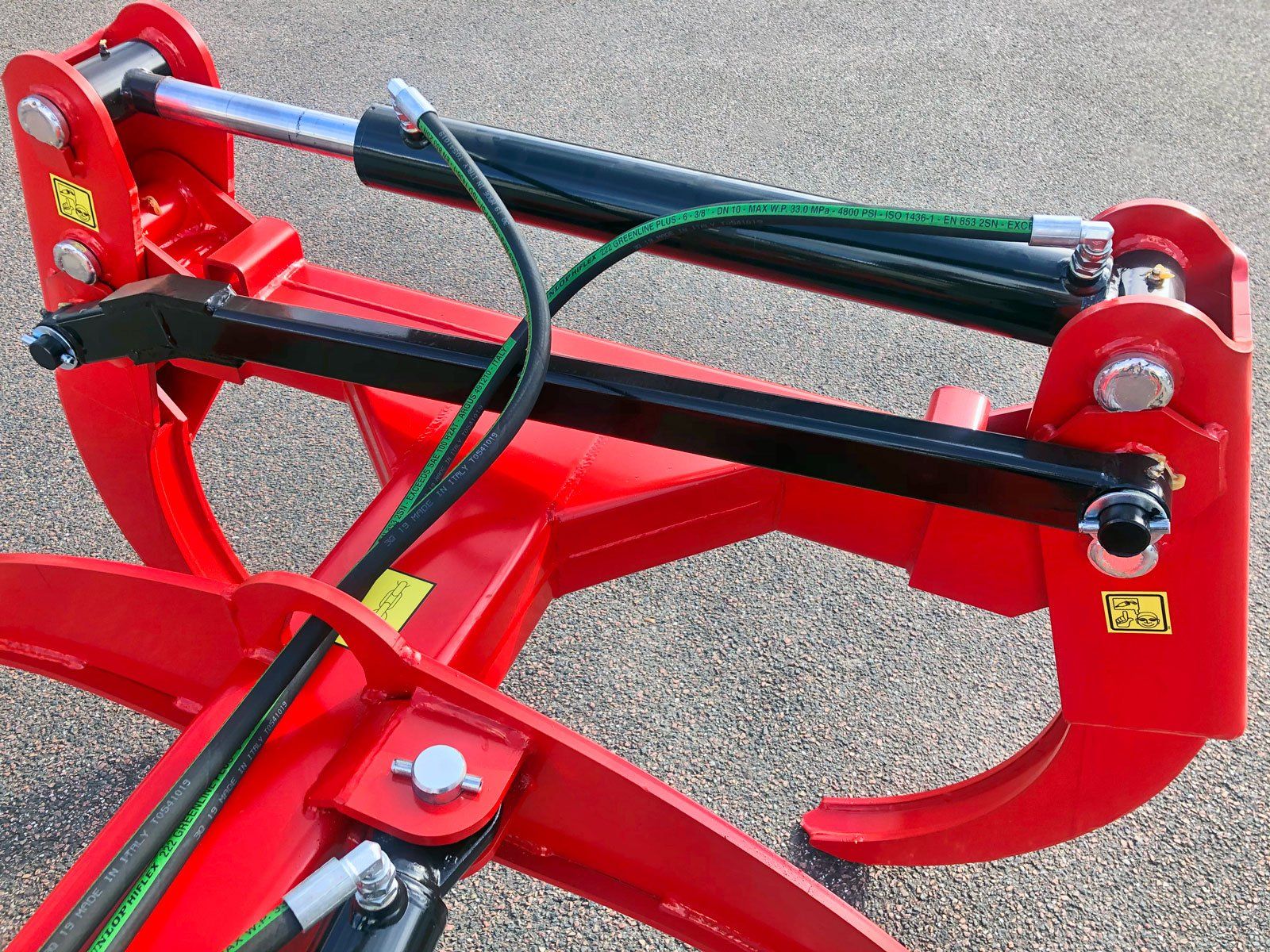 Et nærbillede af en rød skovtangsmaskine med et hydraulisk system tilknyttet