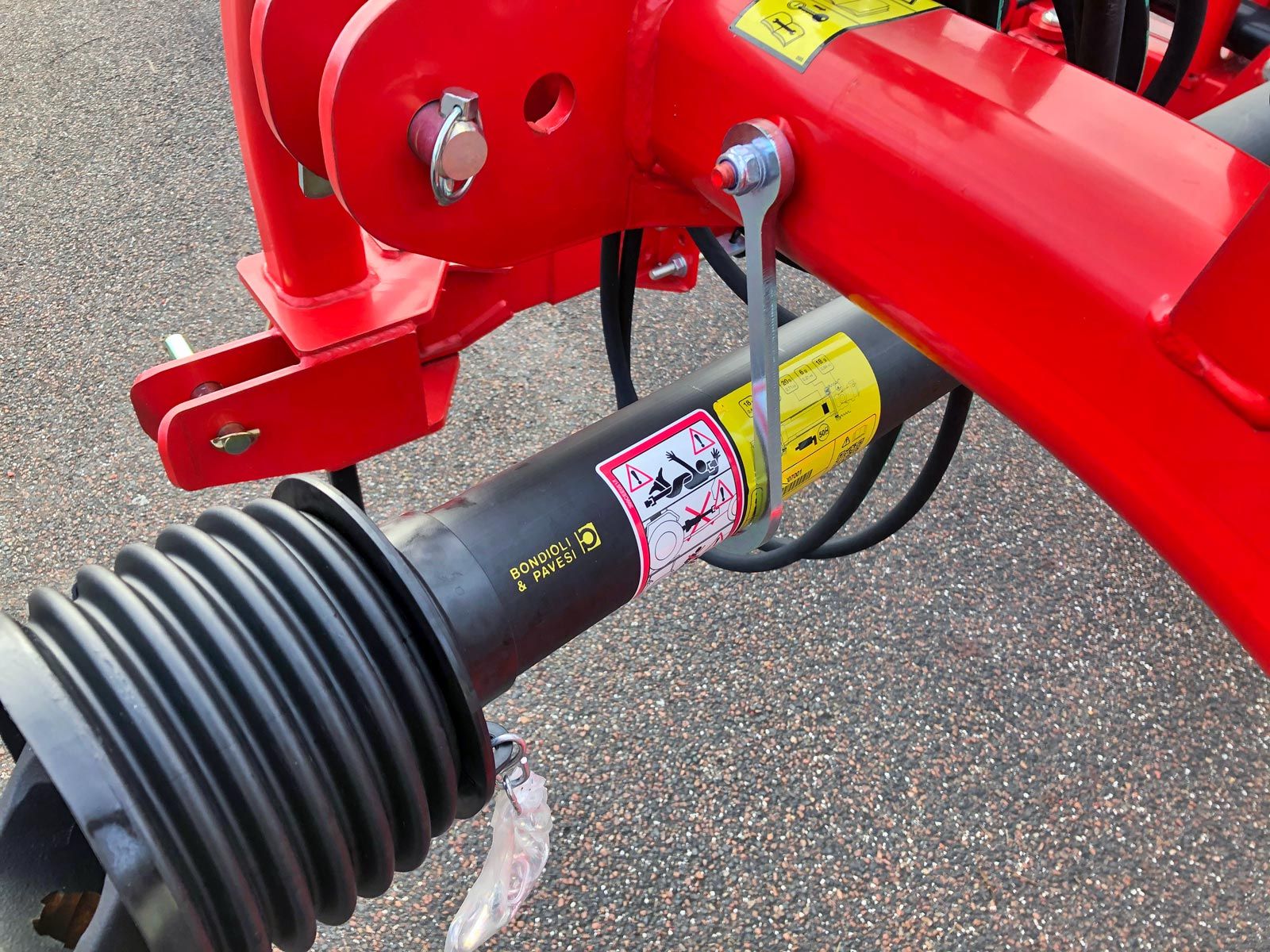 Et nærbillede af en rød maskine med en sort kardanaksel knyttet til den