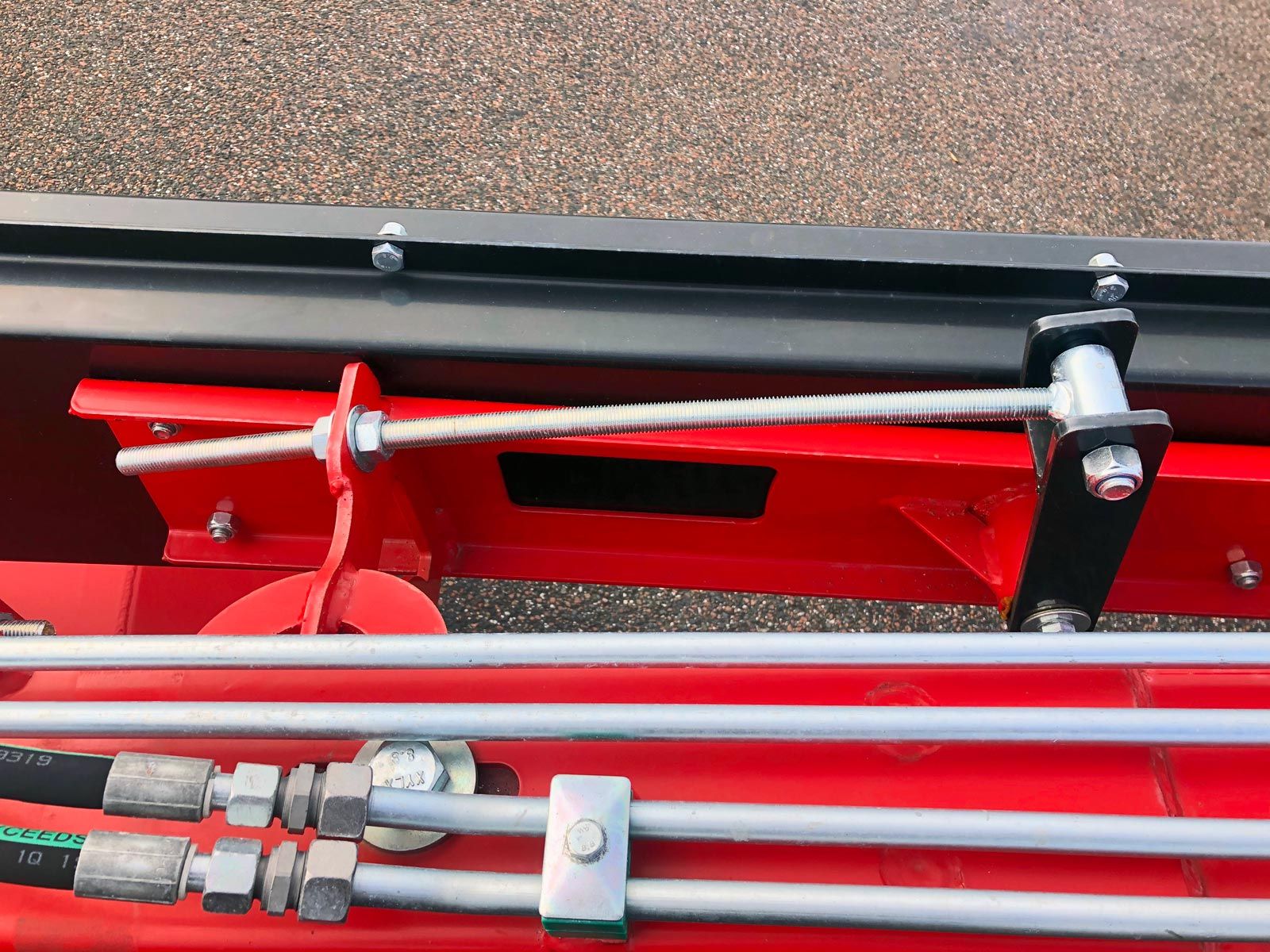 Et nærbillede af en rød maskine med hydrauliske rør knyttet til den.