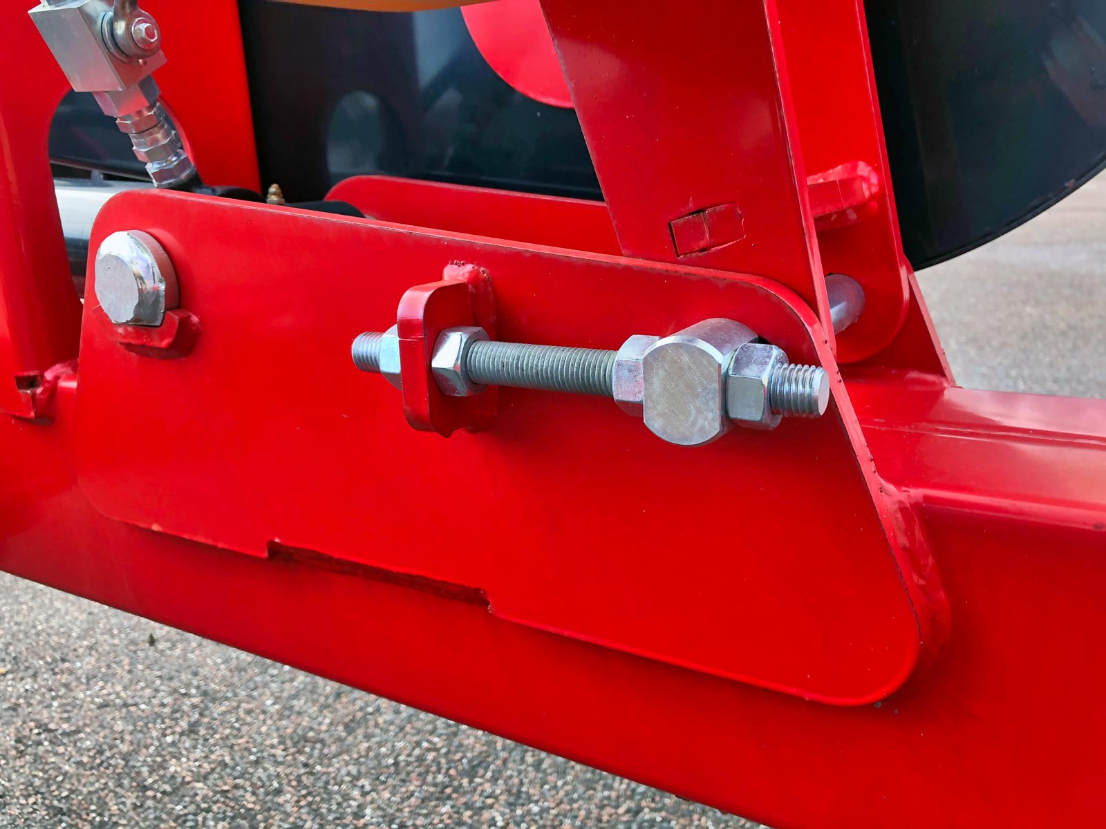 Et nærbillede af en rød maskine med en bolt og møtrik til justering
