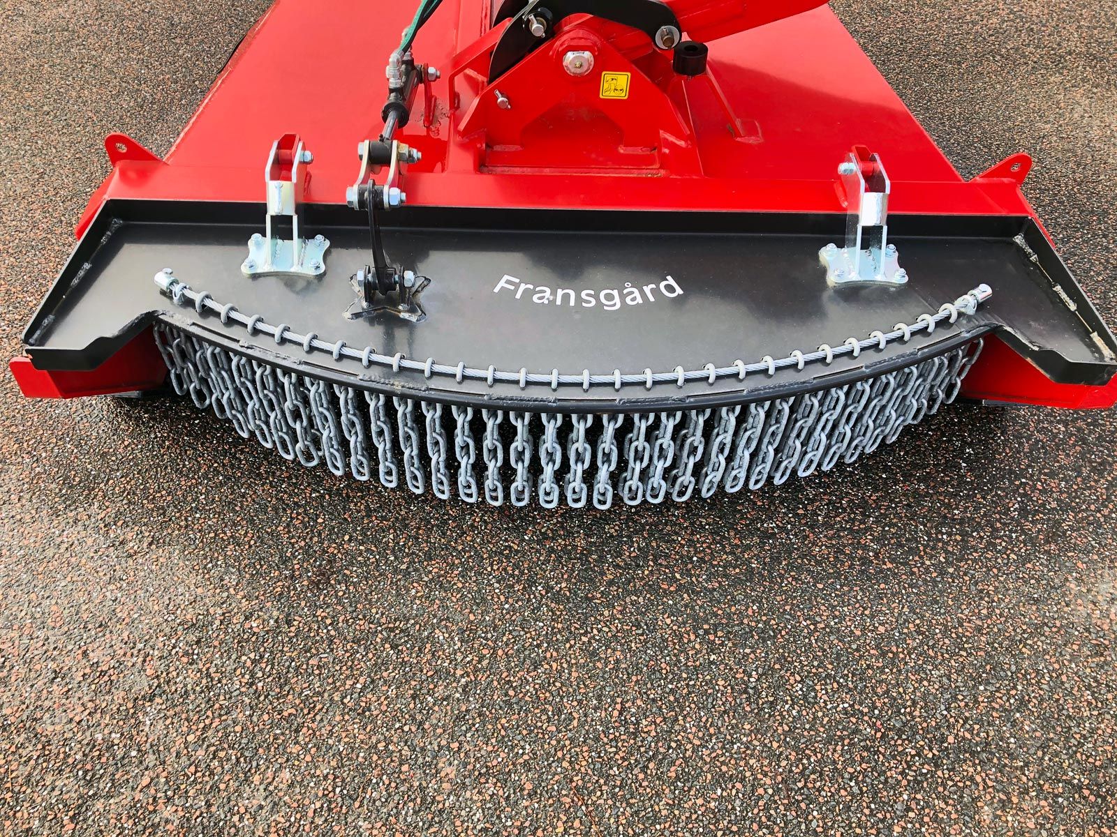 En rød og sort kæderydder placeret på jorden.