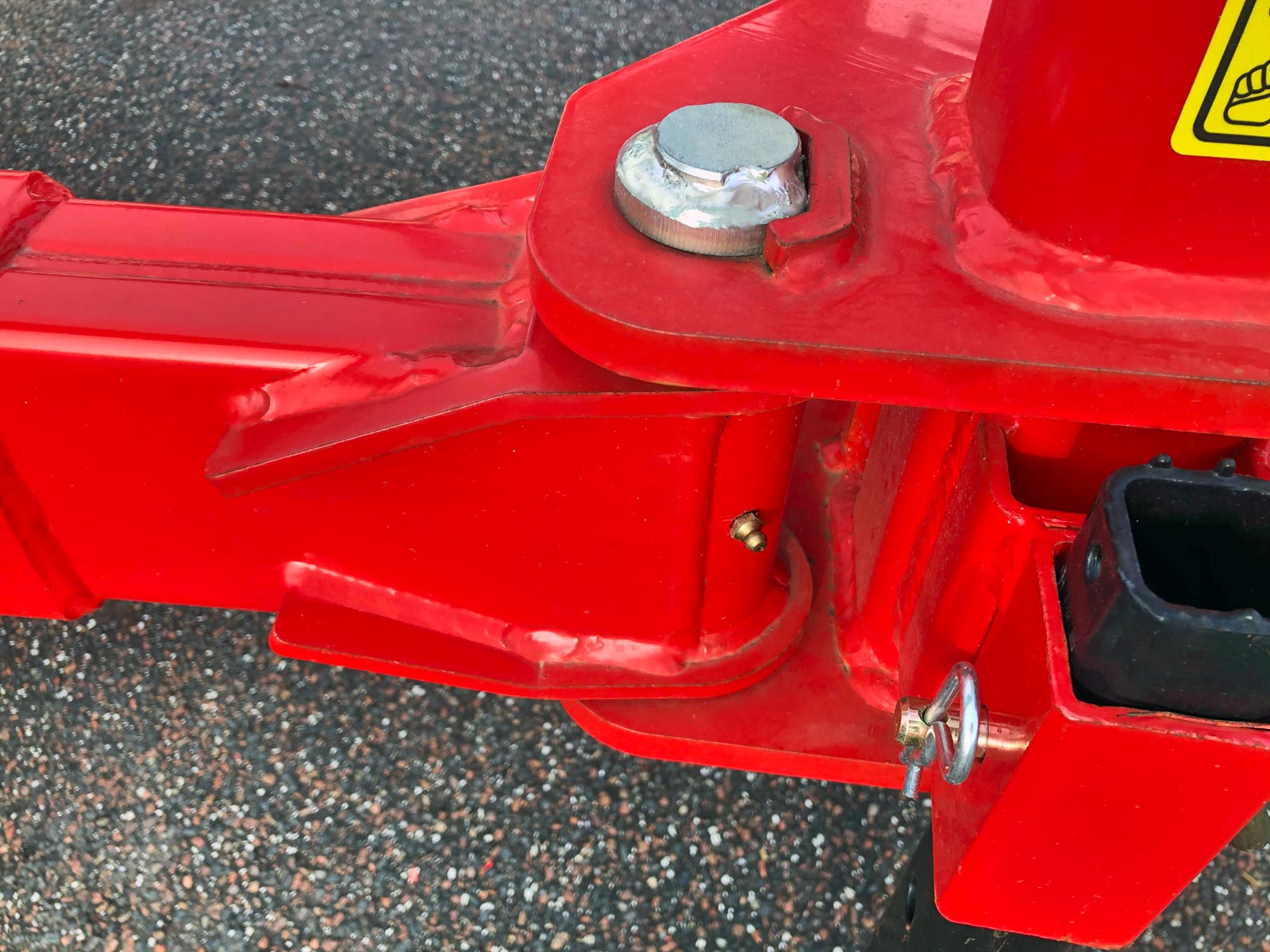 Et nærbillede af en smørenippel placeret i led på en rød maskine