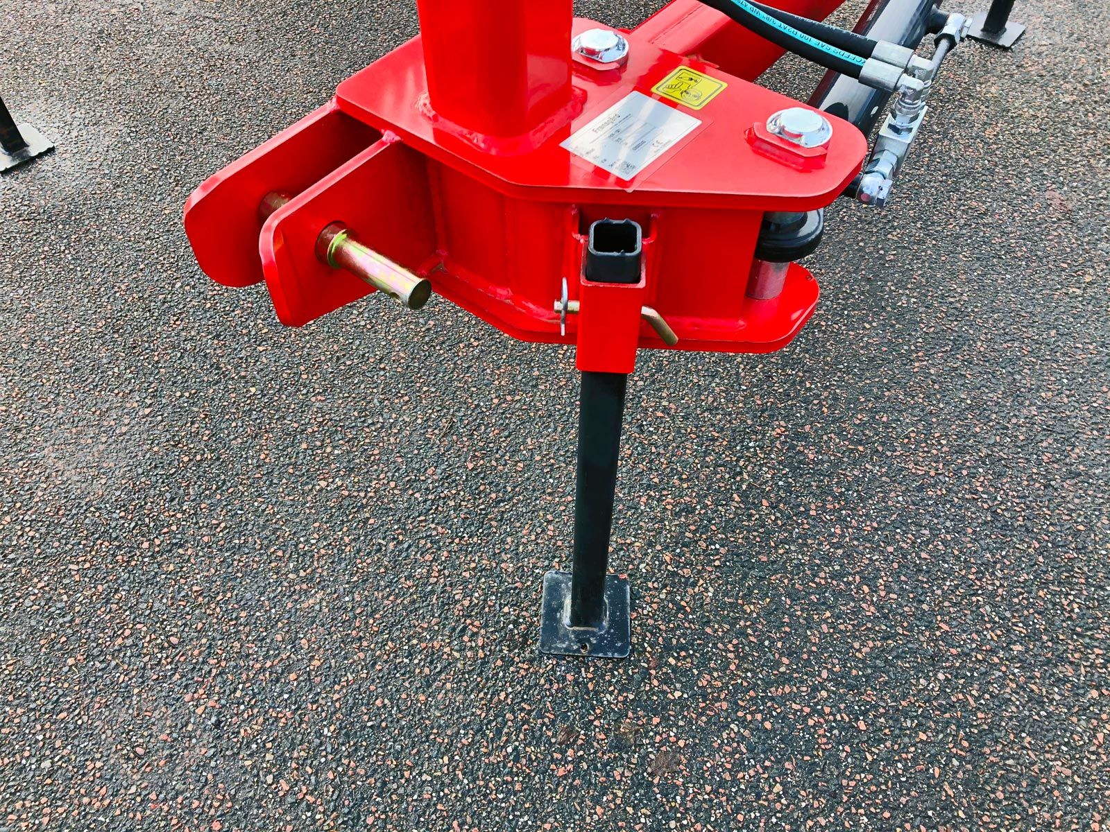 En rød kæderydder maskine parkeret på et støtteben.