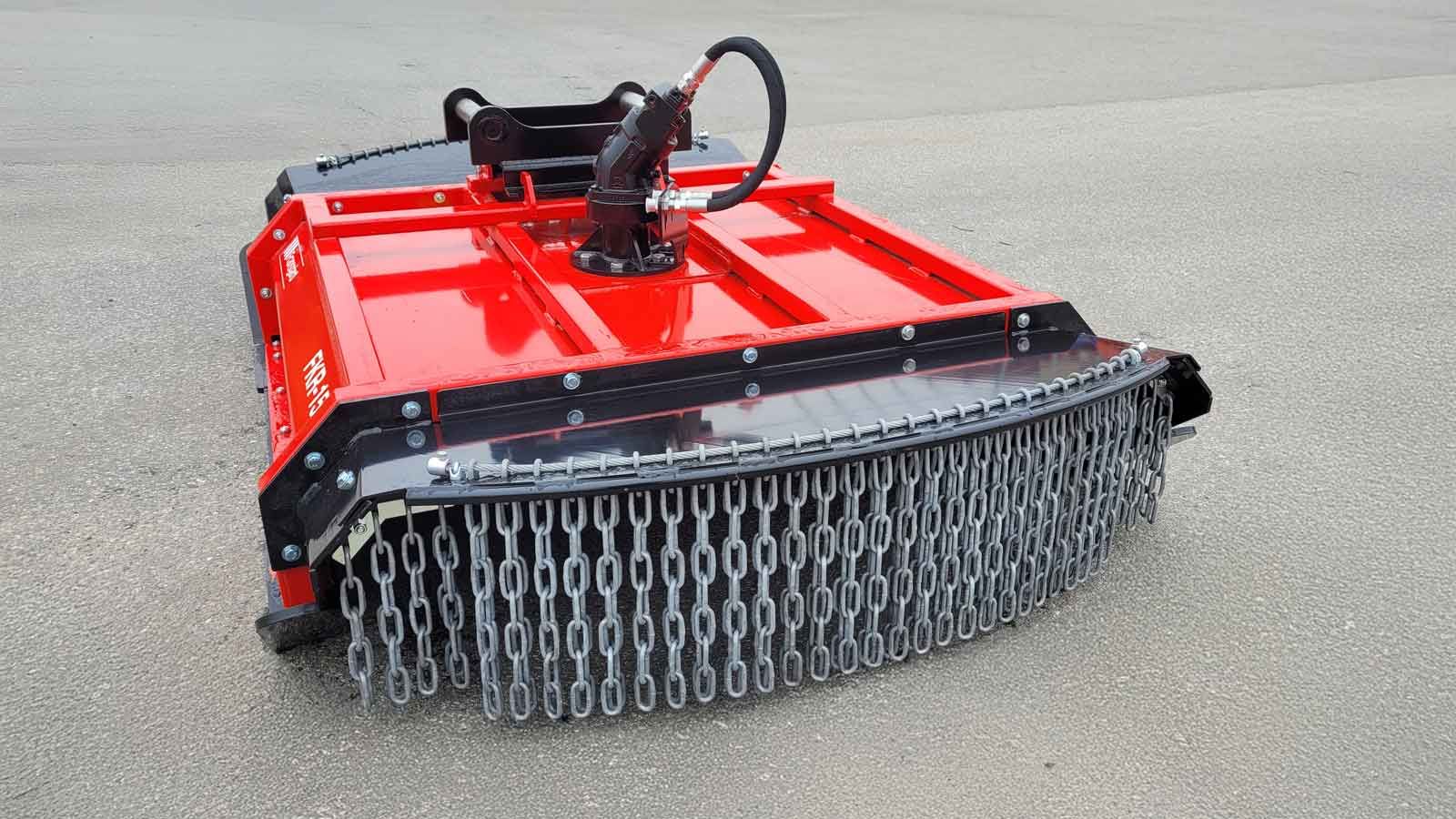 En traktor med en kæderyddermaskine løftet til transport på veje