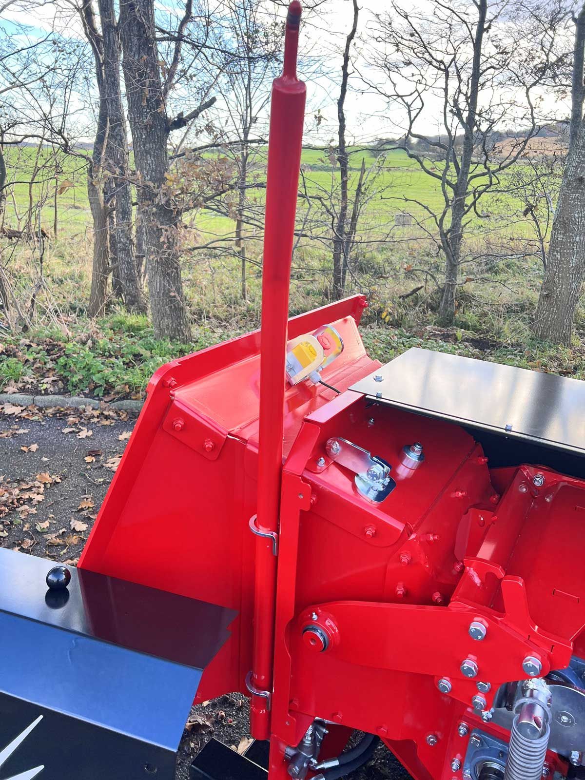 Åbnerstang placeret på flishuggermaskine tæt ved intrækkertragt.