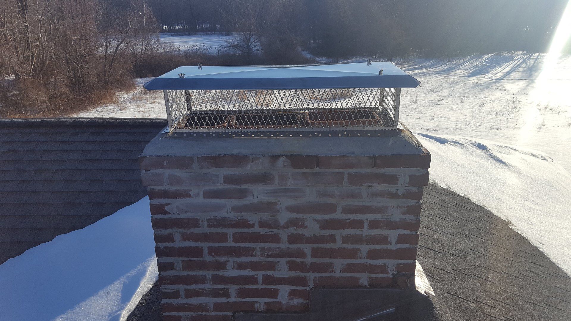 A brick chimney sitting on top of a snow covered roof.