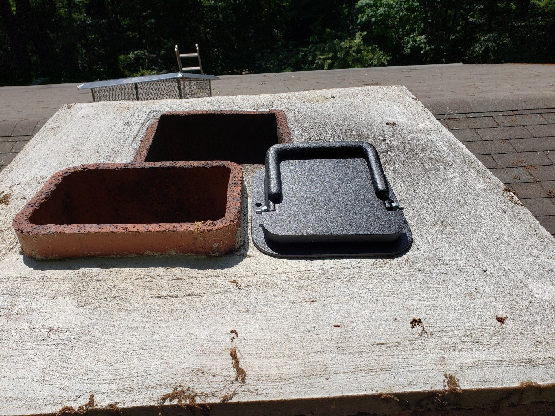 A brick chimney with a black lid on top of it