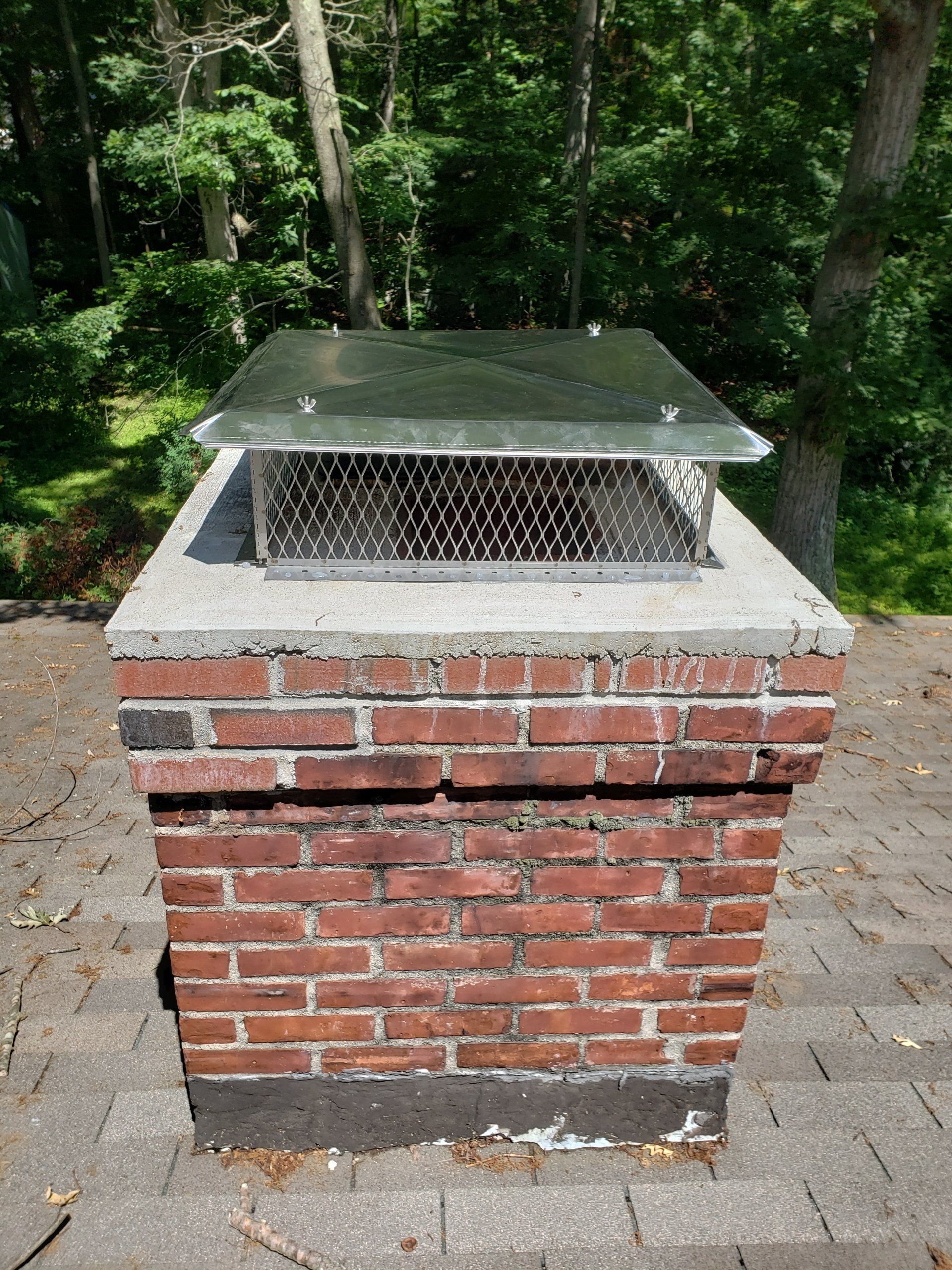 A brick chimney with a metal cover on top of it