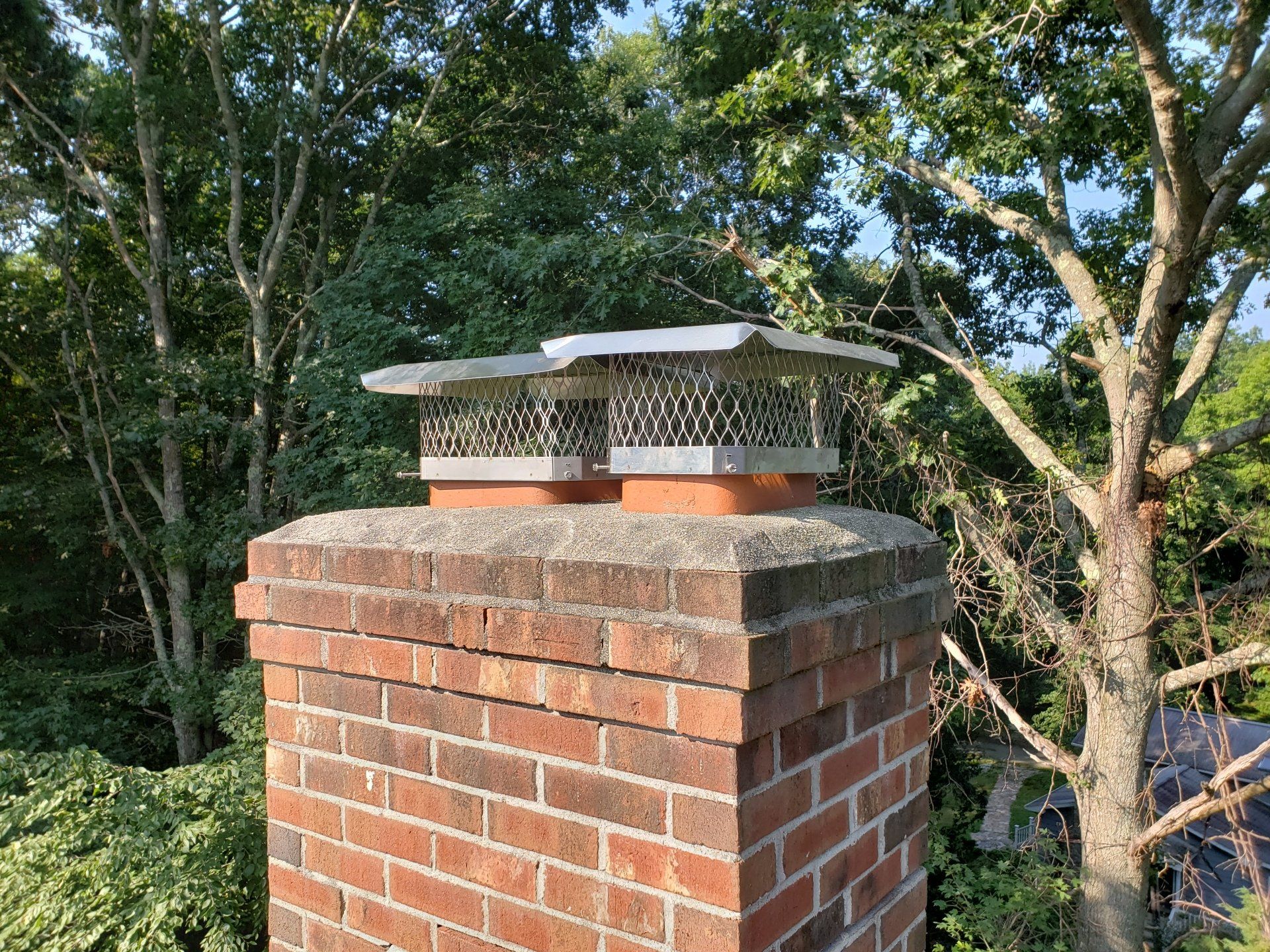A brick chimney with a tree in the background.