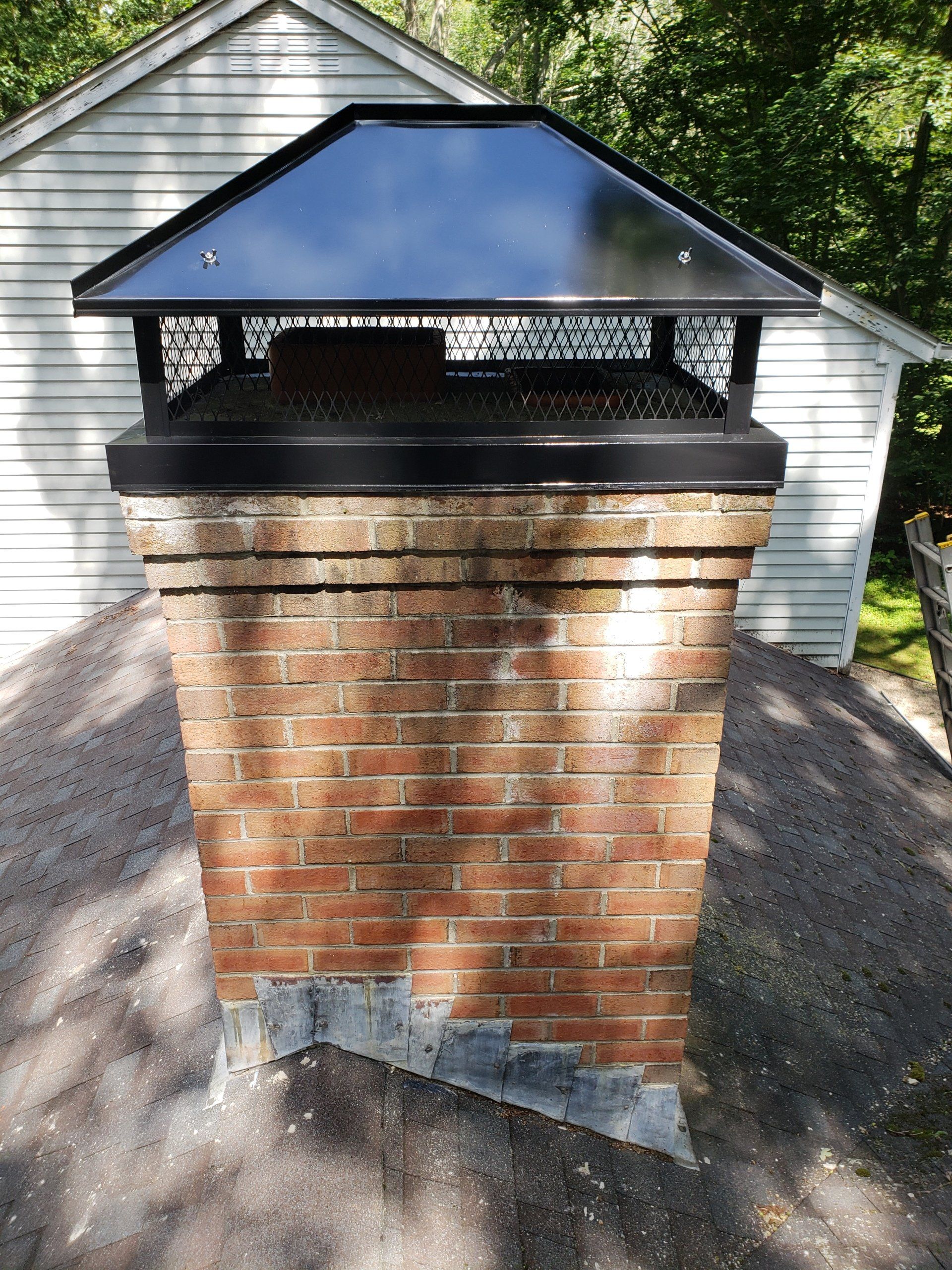 A brick chimney with a black cap on top of it.