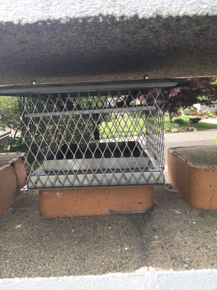 A brick chimney with a metal grate on top of it.