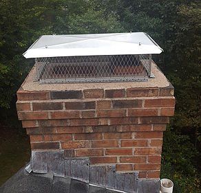 A brick chimney with a metal cover on top of it.