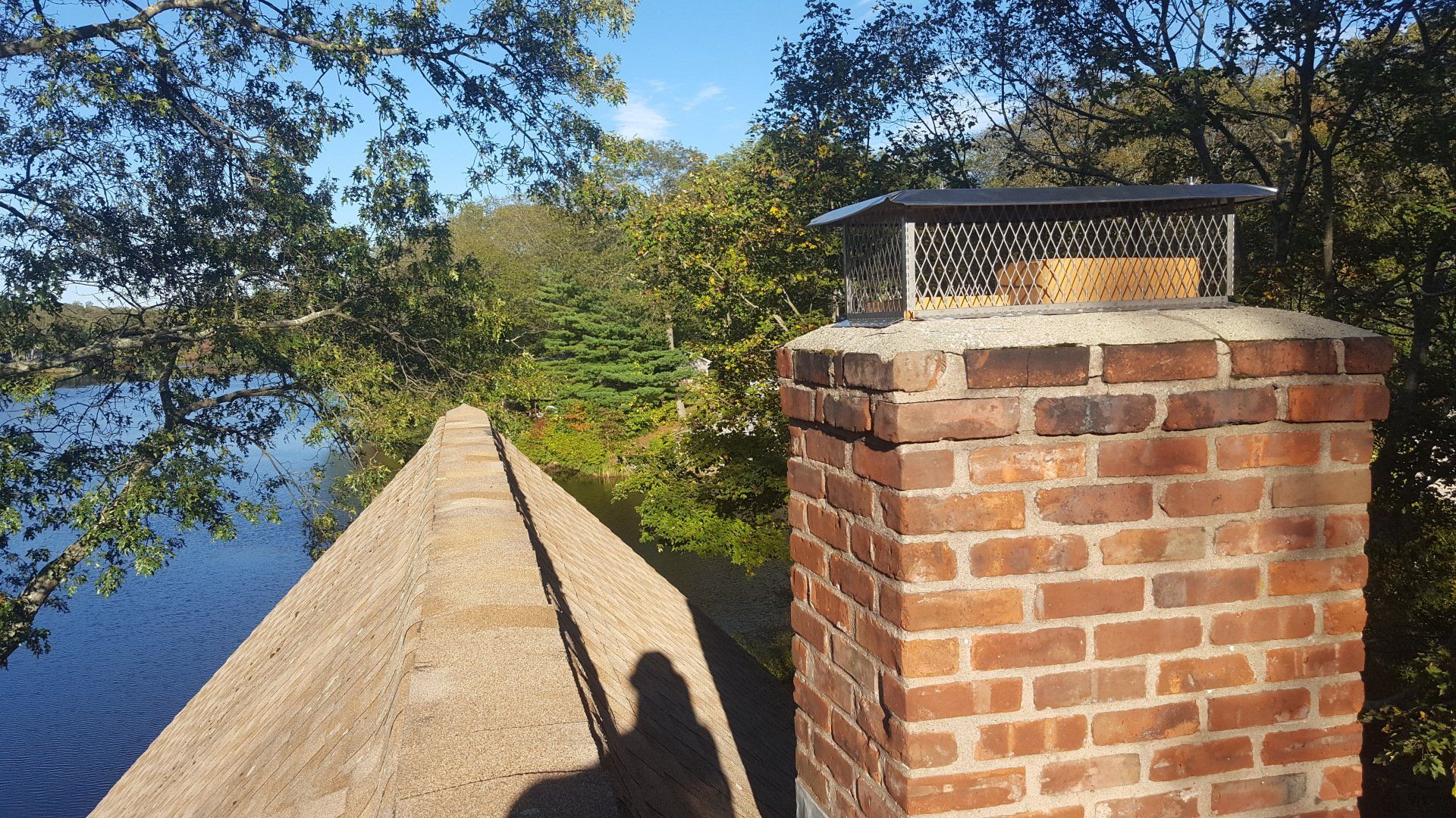 A brick chimney with a thatched roof next to a body of water