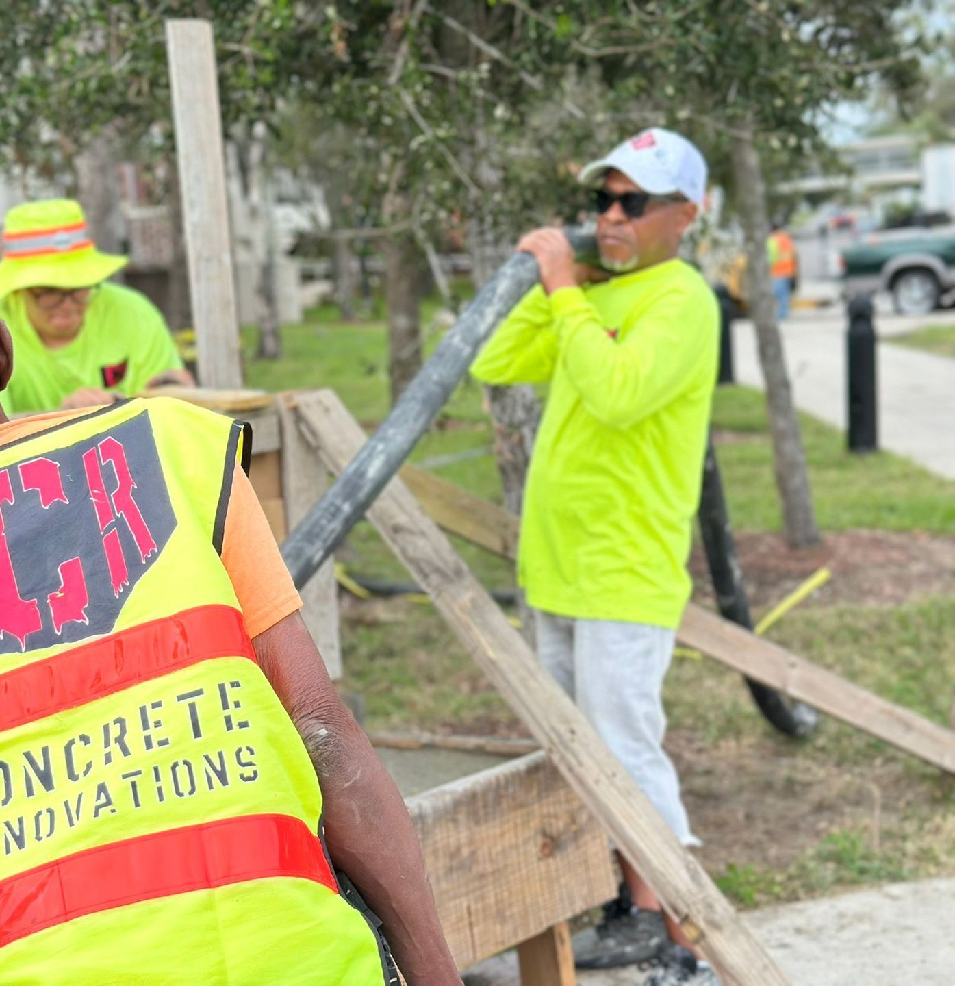A group of construction workers are working on a concrete sidewalk