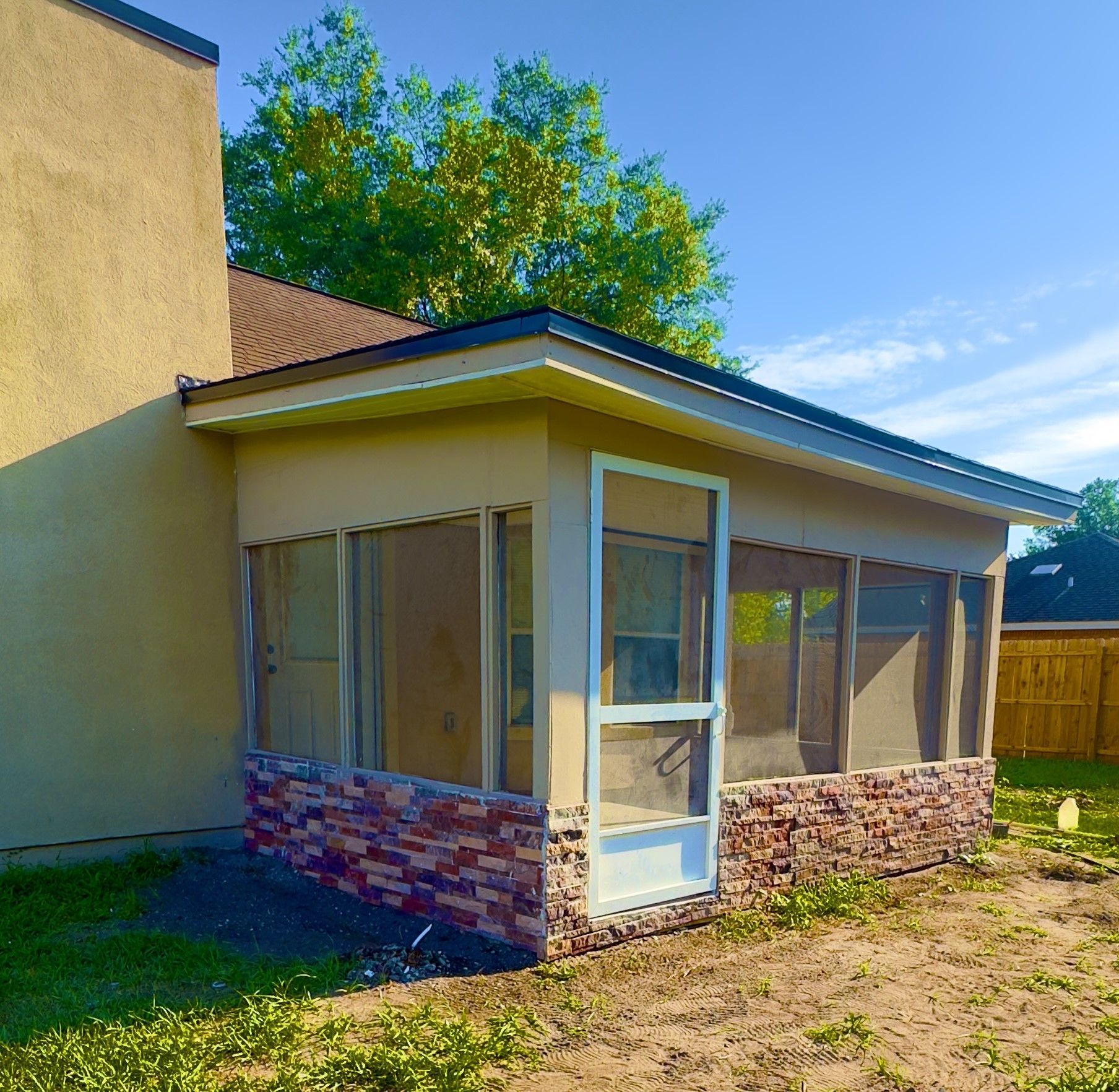 A screened in porch in the backyard of a house