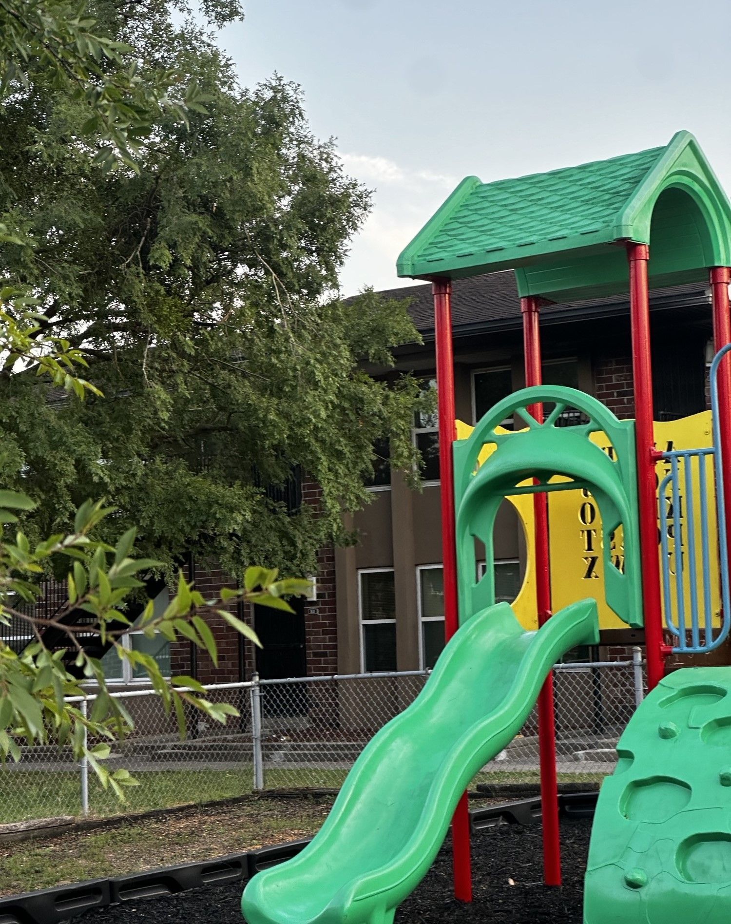 A playground with a green slide and red poles