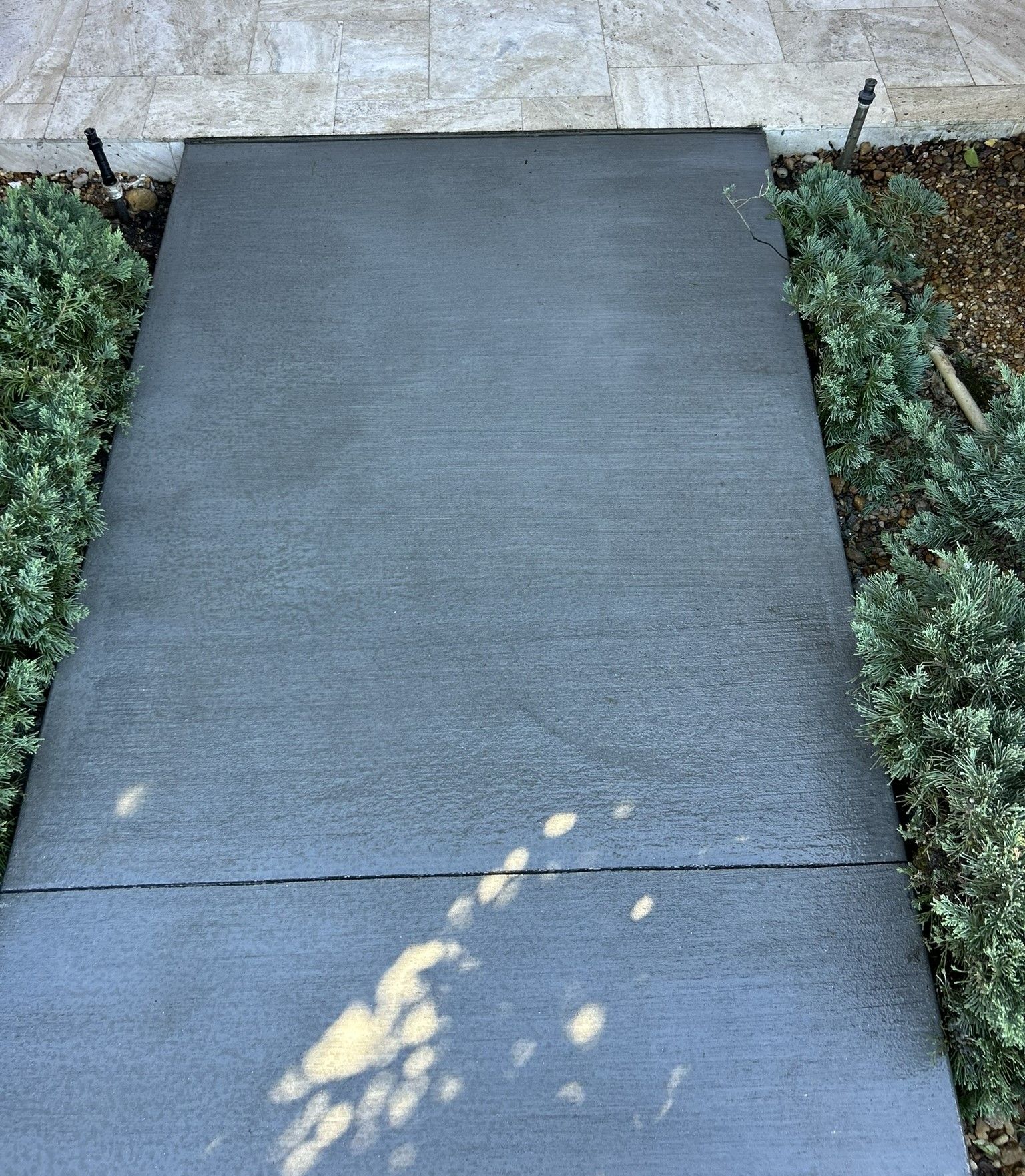 A man is working on a concrete sidewalk in front of a building.