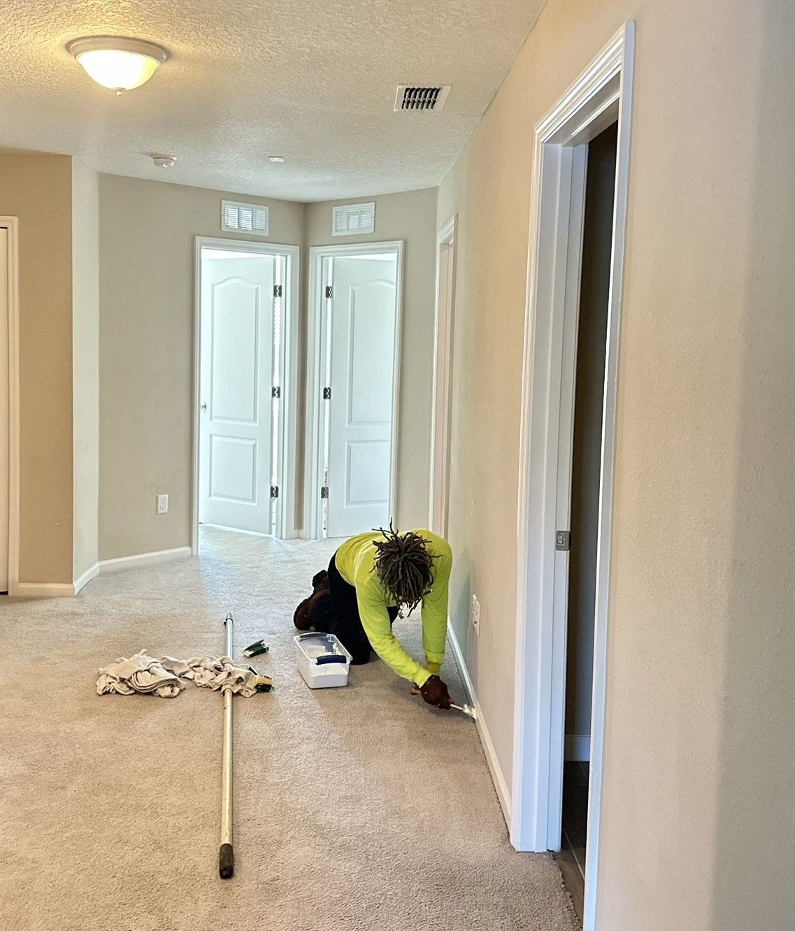 A person is laying on the floor painting in a hallway.