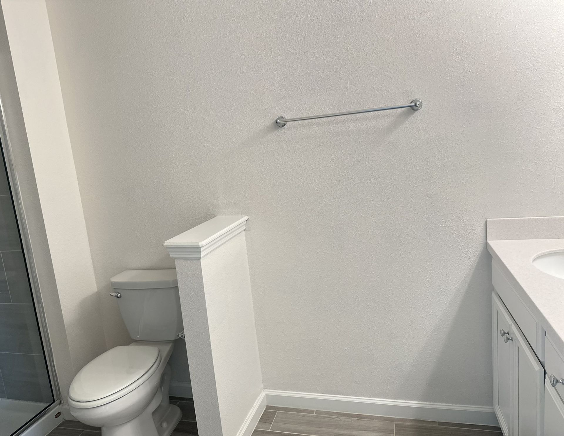 Bathroom with a white toilet, sink, and wall with a silver towel rack.