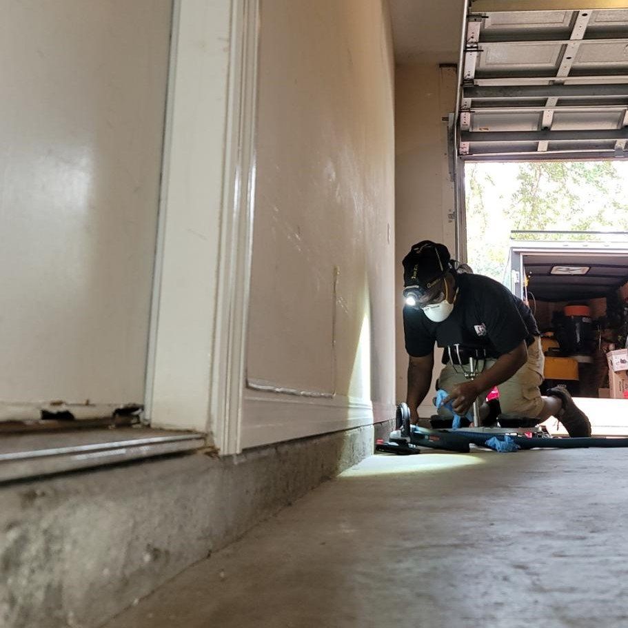 A man is kneeling down in a hallway next to a garage door.