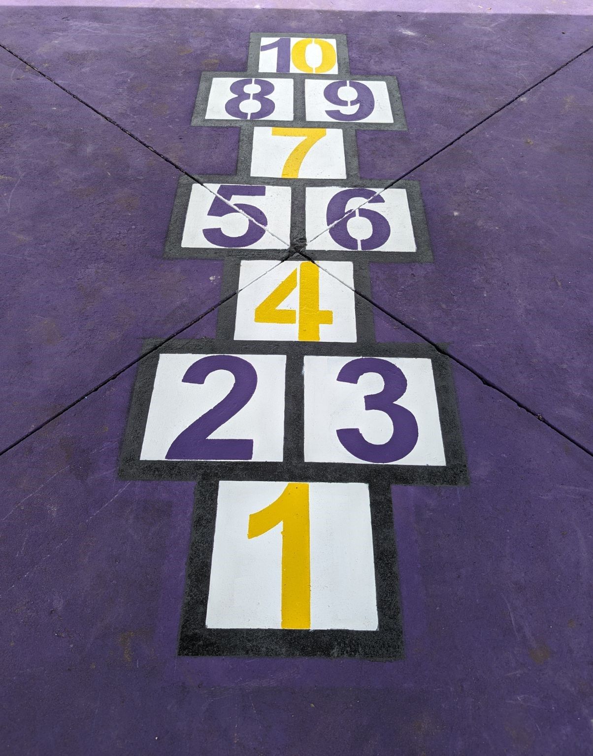 A purple and white hopscotch game is painted on the ground